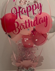 Red and Pink small balloons inside a transparent balloon saying happy birthday with red ribbon and pink paper with 6 pink roses